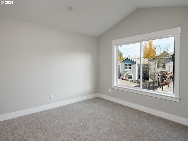 carpeted spare room featuring lofted ceiling