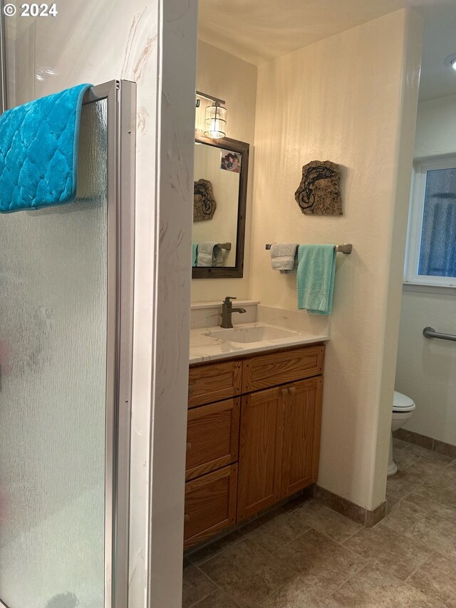 bathroom with tile patterned flooring, vanity, toilet, and walk in shower