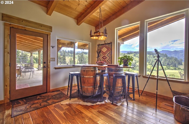 dining area with a mountain view, vaulted ceiling with beams, hardwood / wood-style flooring, and wood ceiling