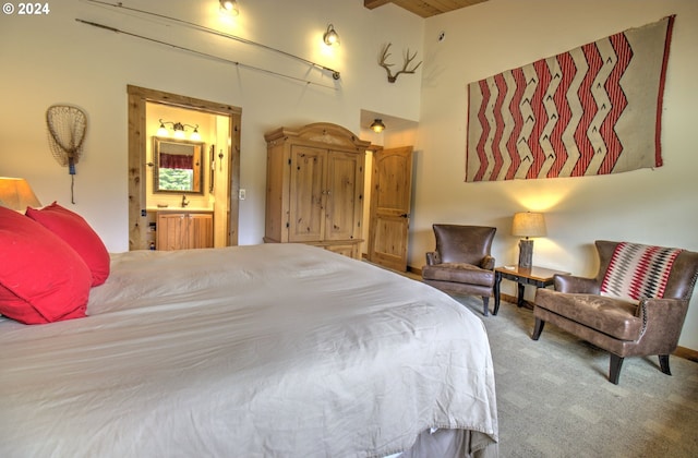 bedroom featuring carpet, beam ceiling, and ensuite bath