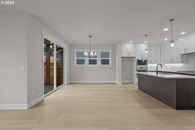 kitchen with white cabinetry, backsplash, hanging light fixtures, and stainless steel appliances