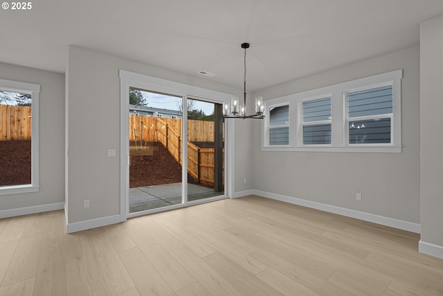 unfurnished dining area with an inviting chandelier and light hardwood / wood-style floors