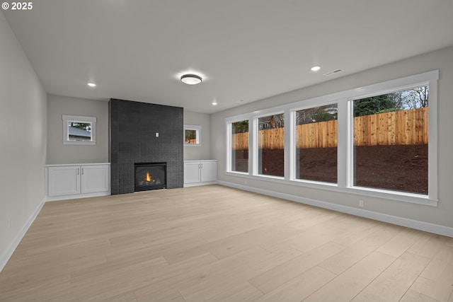 unfurnished living room featuring light hardwood / wood-style floors and a large fireplace