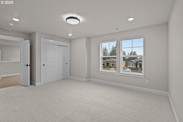 unfurnished bedroom with a closet and light colored carpet