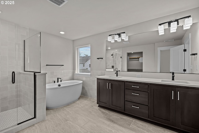 bathroom featuring separate shower and tub, vanity, and tile walls