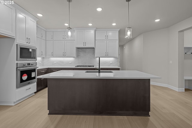 kitchen featuring sink, appliances with stainless steel finishes, white cabinets, and pendant lighting