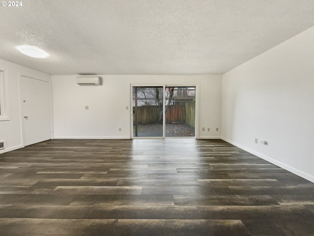 unfurnished room featuring dark hardwood / wood-style flooring, a textured ceiling, and a wall unit AC