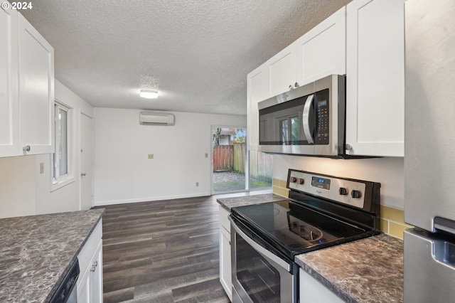 kitchen featuring dark wood-type flooring, white cabinets, a textured ceiling, appliances with stainless steel finishes, and a wall unit AC