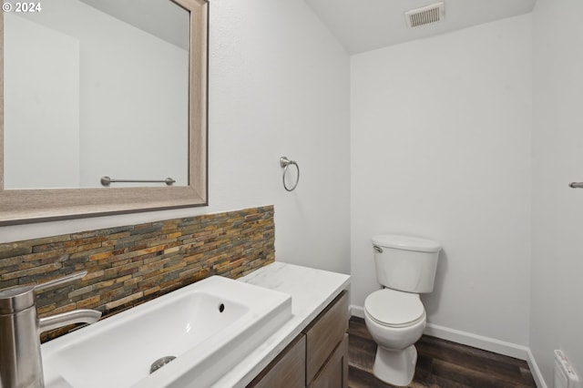 bathroom featuring vanity, hardwood / wood-style flooring, toilet, and tasteful backsplash