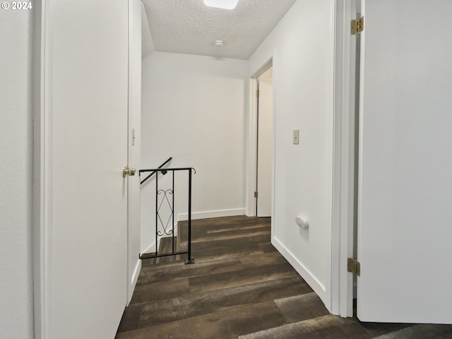 hallway with dark hardwood / wood-style flooring and a textured ceiling