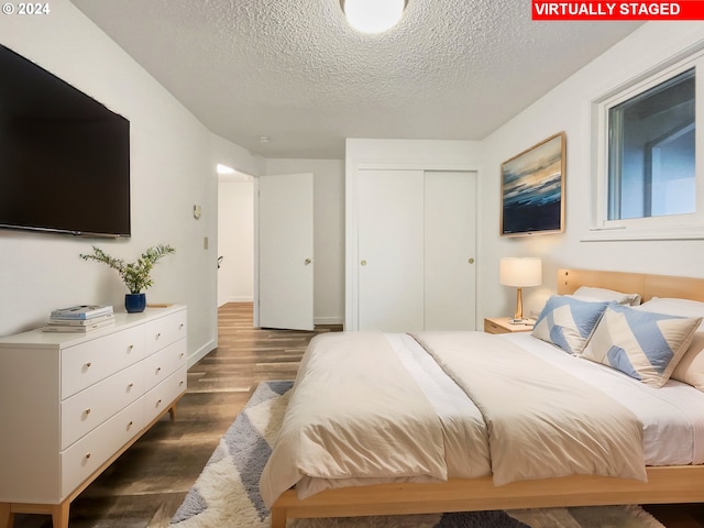 bedroom with a textured ceiling, a closet, and dark wood-type flooring