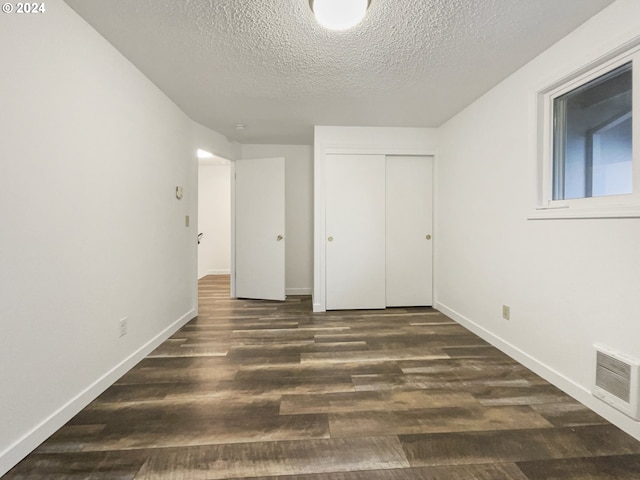 unfurnished bedroom with a textured ceiling, a closet, and dark wood-type flooring