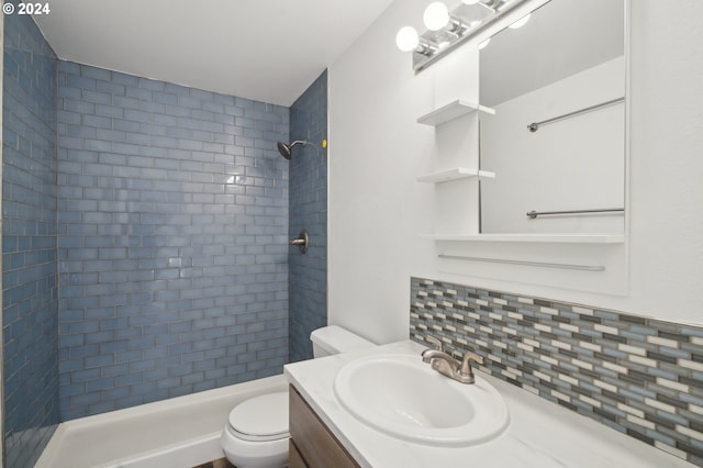 bathroom with vanity, toilet, backsplash, and a tile shower