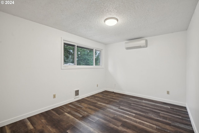 unfurnished room with a wall mounted air conditioner, a textured ceiling, and dark hardwood / wood-style flooring