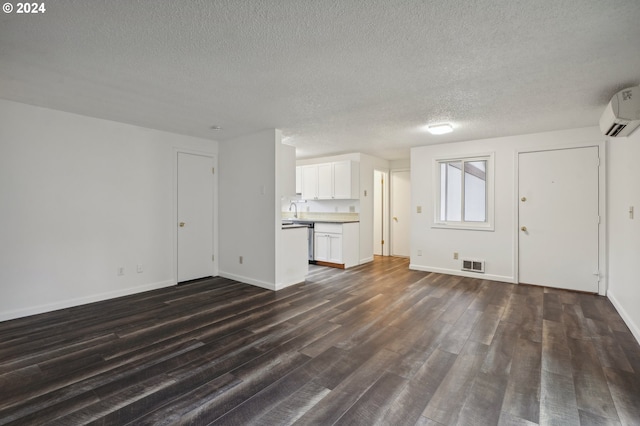 unfurnished living room featuring dark hardwood / wood-style floors, sink, a textured ceiling, and a wall mounted AC