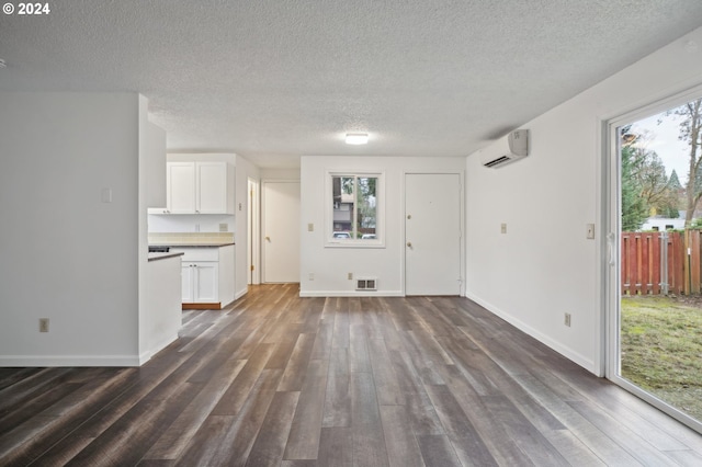 unfurnished living room with dark hardwood / wood-style floors, a textured ceiling, and a wall mounted AC