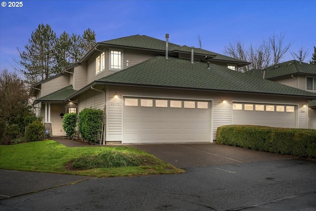 view of front of house with a garage, driveway, and roof with shingles