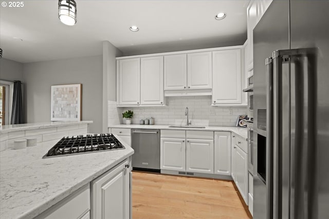 kitchen with appliances with stainless steel finishes, white cabinetry, and a sink