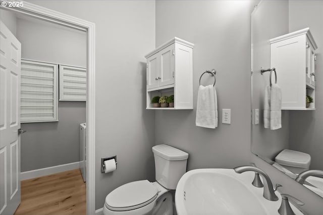 bathroom featuring toilet, baseboards, a sink, and wood finished floors