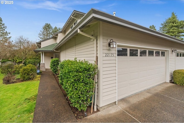 view of property exterior with a garage, a lawn, and driveway