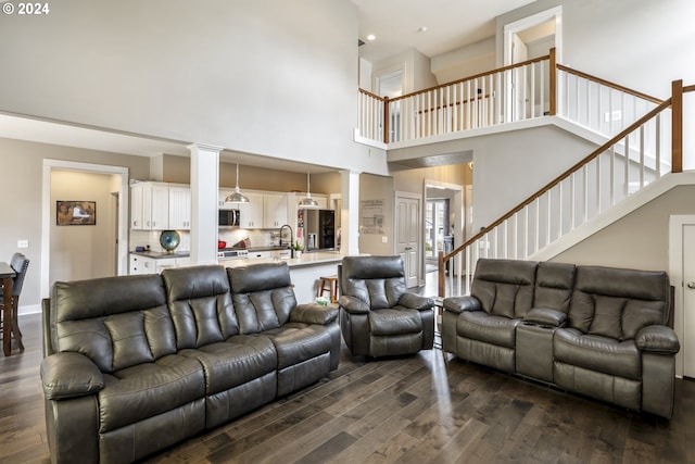 living room with a high ceiling, dark wood-type flooring, decorative columns, and sink