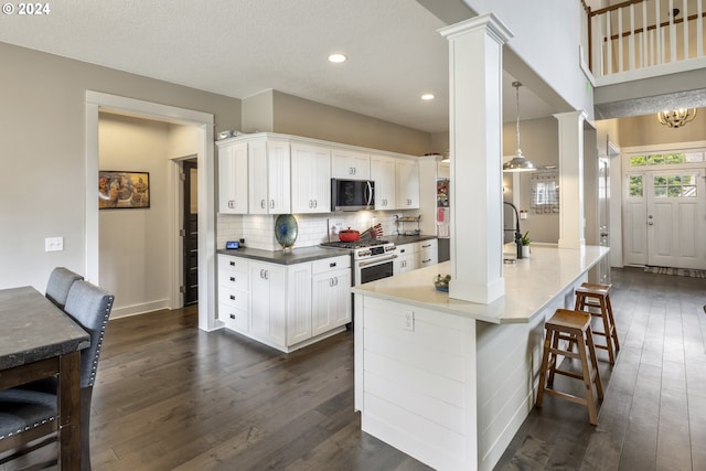 kitchen with white cabinetry, tasteful backsplash, decorative columns, pendant lighting, and dark wood-type flooring