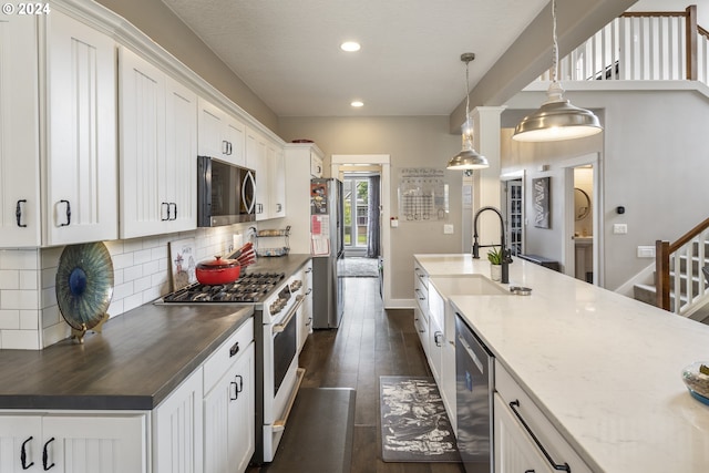 kitchen with appliances with stainless steel finishes, white cabinetry, dark hardwood / wood-style floors, tasteful backsplash, and sink