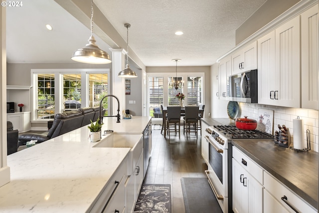 kitchen with backsplash, stainless steel appliances, a textured ceiling, pendant lighting, and dark wood-type flooring