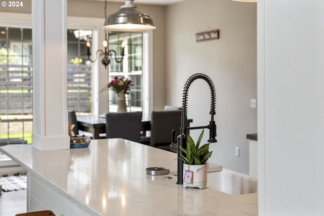 interior space featuring sink, hanging light fixtures, and light stone countertops