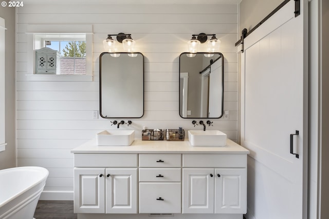 bathroom with wood-type flooring, a washtub, wooden walls, and dual bowl vanity