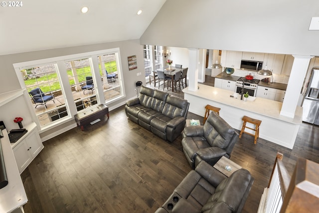 living room with dark hardwood / wood-style flooring, high vaulted ceiling, and ornate columns