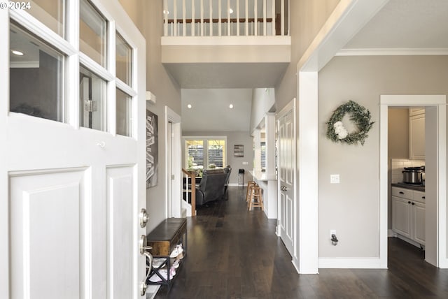 foyer entrance with dark hardwood / wood-style floors, a towering ceiling, and crown molding