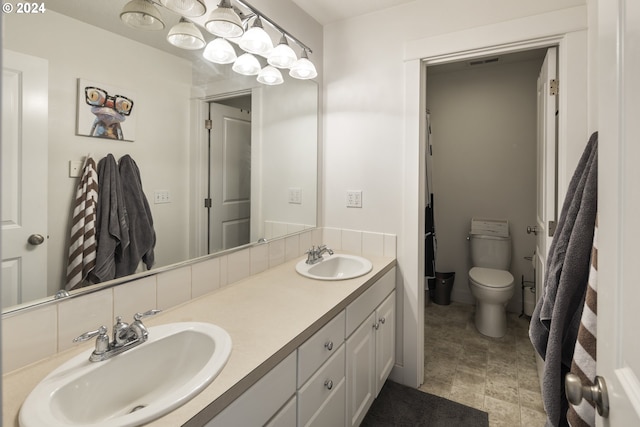 bathroom featuring dual vanity, toilet, and tile patterned floors