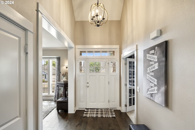 foyer with hardwood / wood-style floors, an inviting chandelier, and a towering ceiling