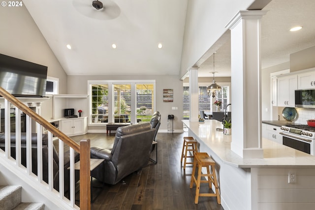 living room with high vaulted ceiling, dark wood-type flooring, and ornate columns