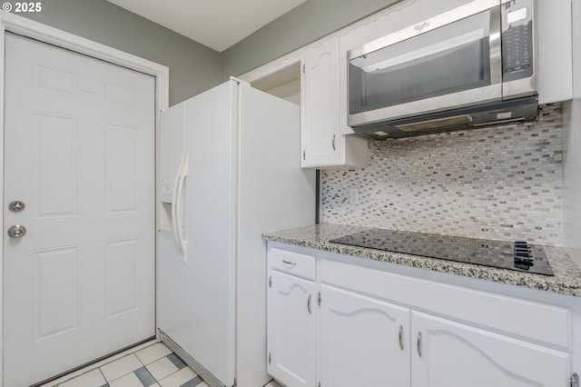 kitchen with tasteful backsplash, white cabinetry, light stone counters, white fridge with ice dispenser, and black electric stovetop