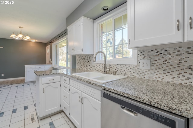 kitchen with sink, light tile patterned floors, stainless steel dishwasher, kitchen peninsula, and white cabinets