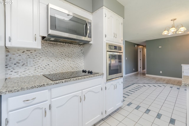 kitchen featuring light stone counters, an inviting chandelier, appliances with stainless steel finishes, decorative backsplash, and white cabinets