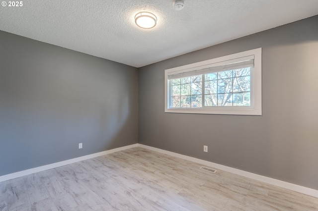 spare room with a textured ceiling and light hardwood / wood-style floors