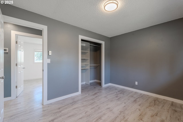 unfurnished bedroom with light hardwood / wood-style flooring, a closet, and a textured ceiling