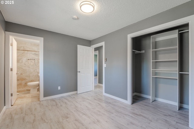 unfurnished bedroom with ensuite bath, light hardwood / wood-style floors, a closet, and a textured ceiling