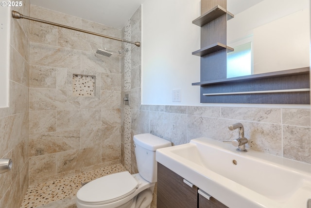 bathroom with vanity, toilet, tile walls, and a tile shower