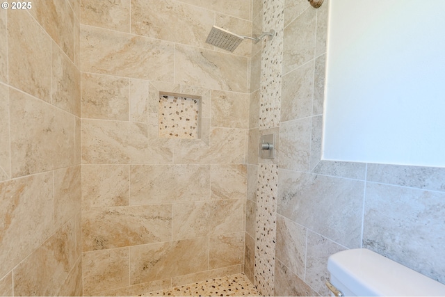 bathroom featuring tiled shower and toilet