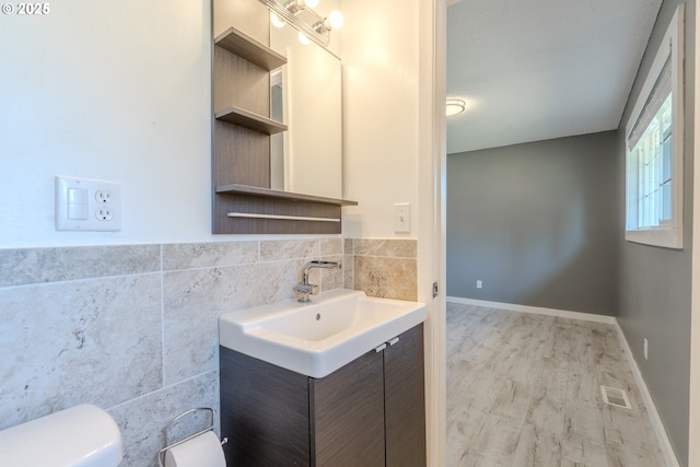 bathroom featuring vanity, hardwood / wood-style floors, tile walls, and toilet