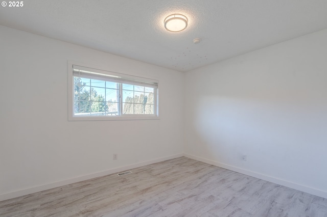 spare room with light hardwood / wood-style flooring and a textured ceiling