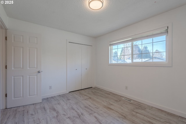 unfurnished bedroom with light hardwood / wood-style floors, a closet, and a textured ceiling