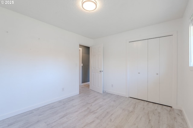 unfurnished bedroom with light hardwood / wood-style floors, a closet, and a textured ceiling