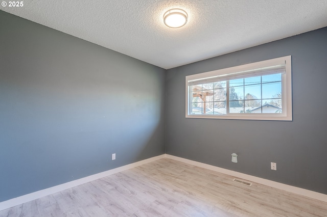 spare room featuring a textured ceiling and light hardwood / wood-style floors