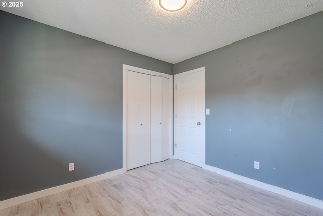 unfurnished bedroom featuring light hardwood / wood-style floors, a textured ceiling, and a closet