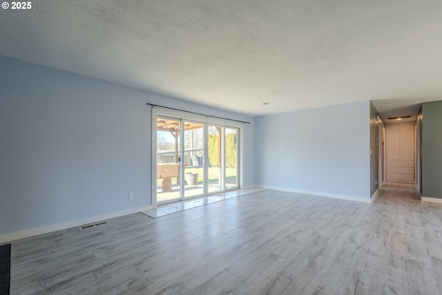 unfurnished room with light hardwood / wood-style flooring and a textured ceiling